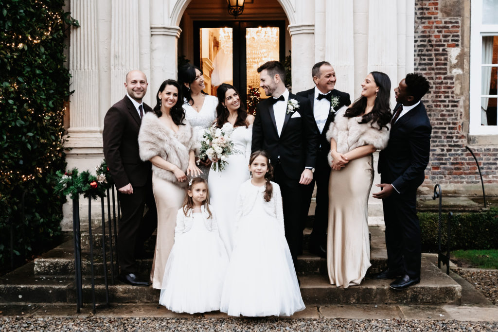 Bride and groom smiling at each other surrounded by family in group photo