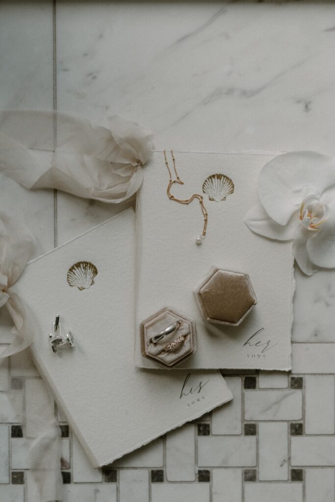 Wedding details flatly including his & her vow book, wedding rings in a. velvet ring box + other jewellery