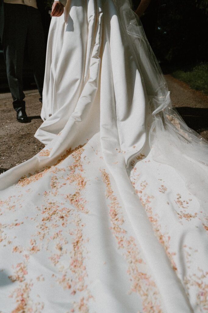 The remnants of pink dried petal confetti gathered onto the train of the brides Pronovias gown