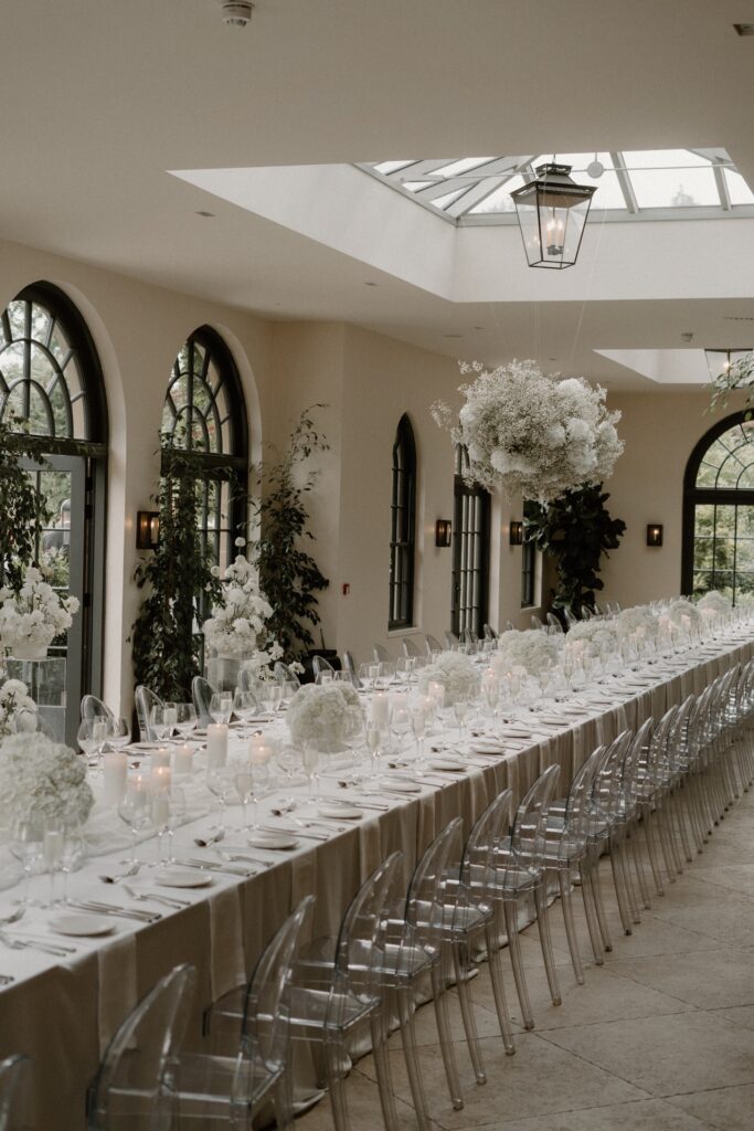 A long table with a white table cloth, white hydrangeas, candles and drinks in The Fig House at Middleton Lodge