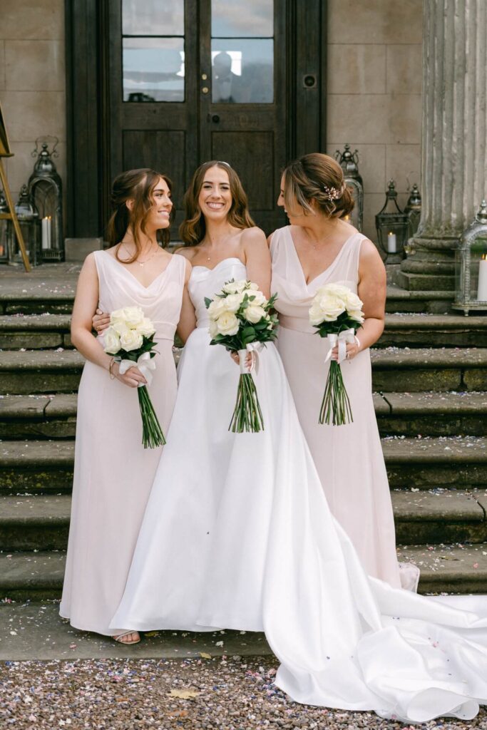 A bride and two bridesmaids in blush pink dresses