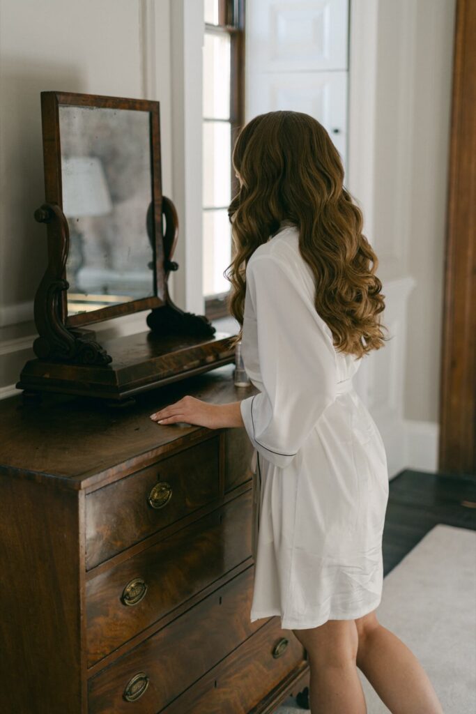 Bride in satin robe looking into a mirror