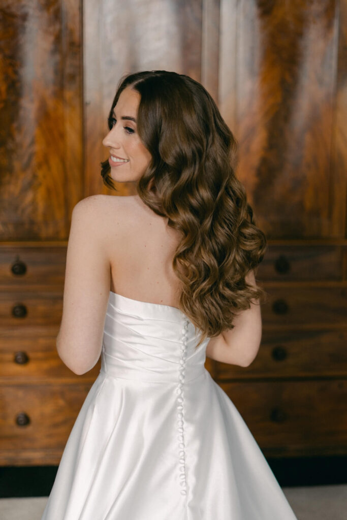 Bride wearing strapless wedding dress looks over her shoulder
