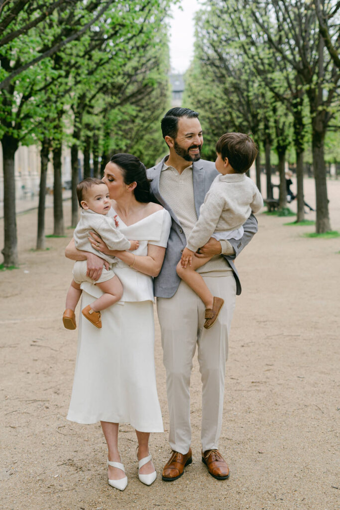 Couple with two young boys smiling in the gardens of Palais Royal, Paris